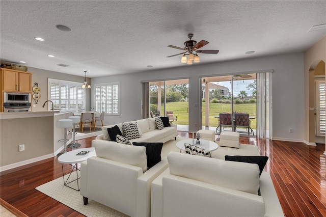 living room with ceiling fan, sink, a textured ceiling, and dark hardwood / wood-style flooring