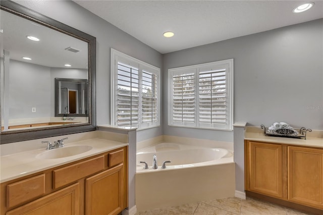 bathroom with a washtub, vanity, and tile patterned flooring