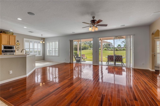 unfurnished living room with ceiling fan, dark hardwood / wood-style flooring, sink, and a textured ceiling