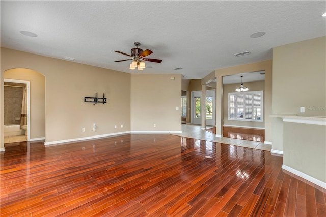 unfurnished living room with hardwood / wood-style flooring, ceiling fan with notable chandelier, and a textured ceiling