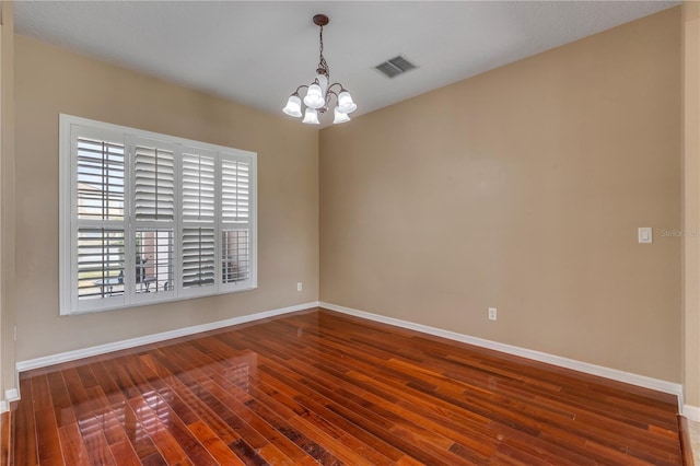 unfurnished room with dark hardwood / wood-style floors and a notable chandelier