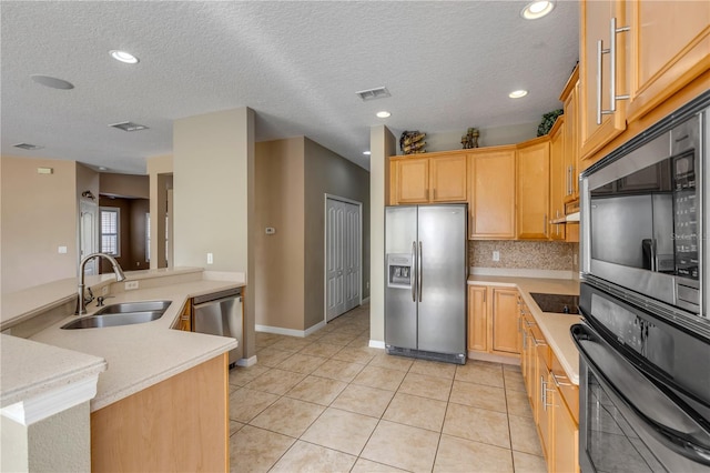 kitchen with light brown cabinetry, sink, light tile patterned floors, kitchen peninsula, and stainless steel appliances