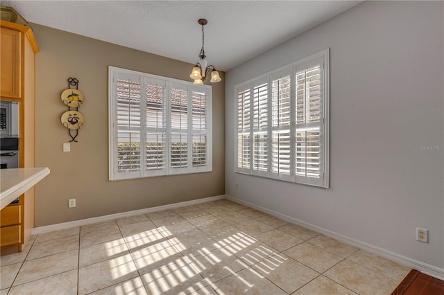 unfurnished dining area featuring an inviting chandelier, light tile patterned floors, and a textured ceiling