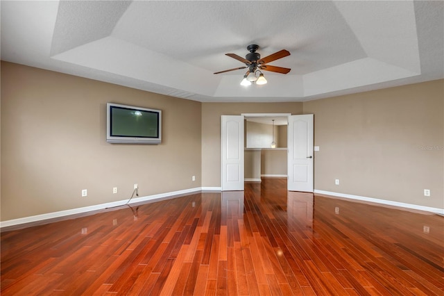 unfurnished room featuring ceiling fan, a tray ceiling, hardwood / wood-style floors, and a textured ceiling