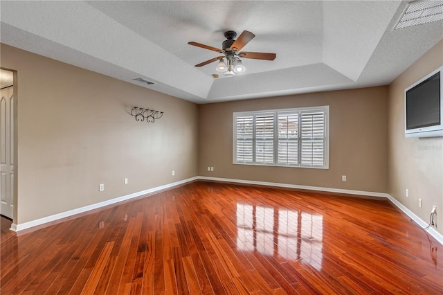 spare room with a raised ceiling, ceiling fan, hardwood / wood-style floors, and a textured ceiling