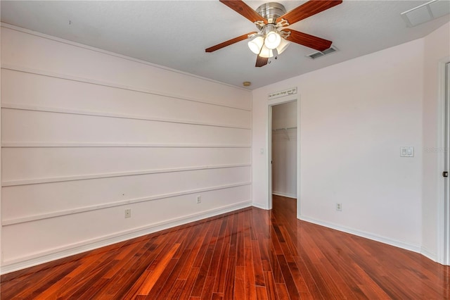 unfurnished bedroom featuring wood-type flooring, a spacious closet, ceiling fan, and a closet