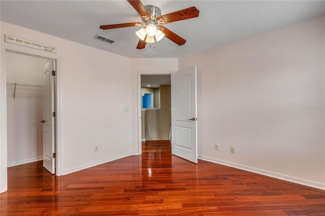 unfurnished bedroom with wood-type flooring, a spacious closet, ceiling fan, and a closet