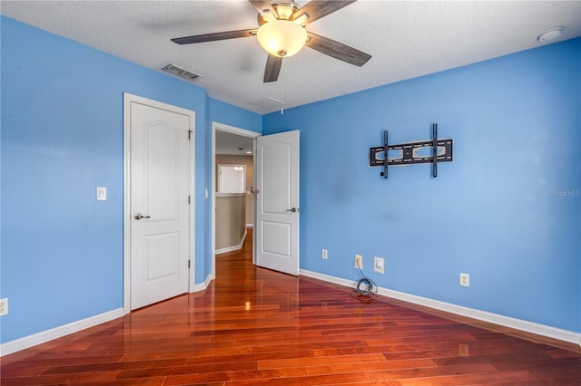 unfurnished bedroom featuring ceiling fan, hardwood / wood-style flooring, and a textured ceiling