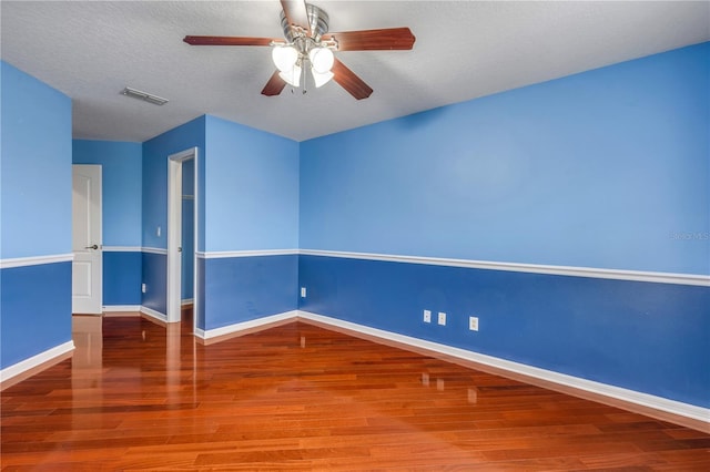 empty room featuring ceiling fan, hardwood / wood-style floors, and a textured ceiling