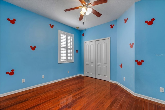 unfurnished bedroom with ceiling fan, hardwood / wood-style floors, a closet, and a textured ceiling