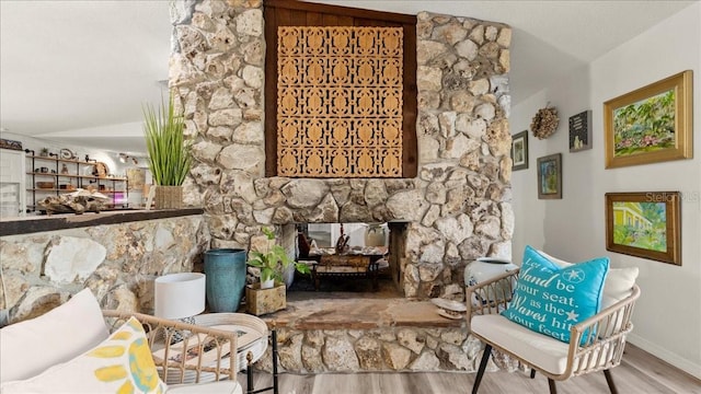 sitting room featuring vaulted ceiling, hardwood / wood-style floors, and a fireplace