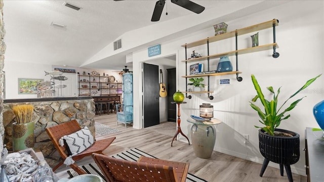 interior space with ceiling fan, lofted ceiling, a textured ceiling, and light wood-type flooring