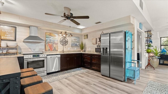 kitchen featuring sink, stainless steel appliances, light hardwood / wood-style floors, and wall chimney exhaust hood