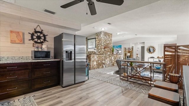 kitchen featuring dark brown cabinetry, lofted ceiling, stainless steel fridge with ice dispenser, a textured ceiling, and light hardwood / wood-style floors