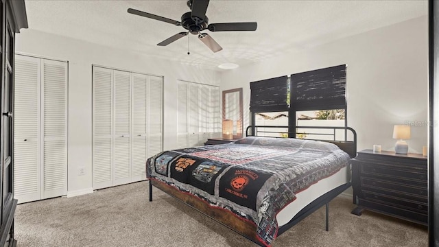 carpeted bedroom with multiple closets, ceiling fan, and a textured ceiling