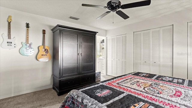 bedroom with two closets, a textured ceiling, ceiling fan, and carpet flooring