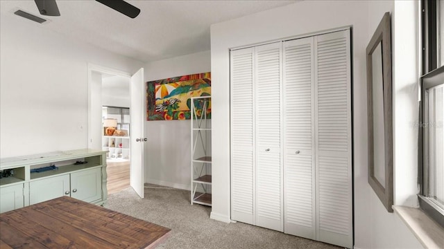 interior space with ceiling fan, green cabinets, and light carpet