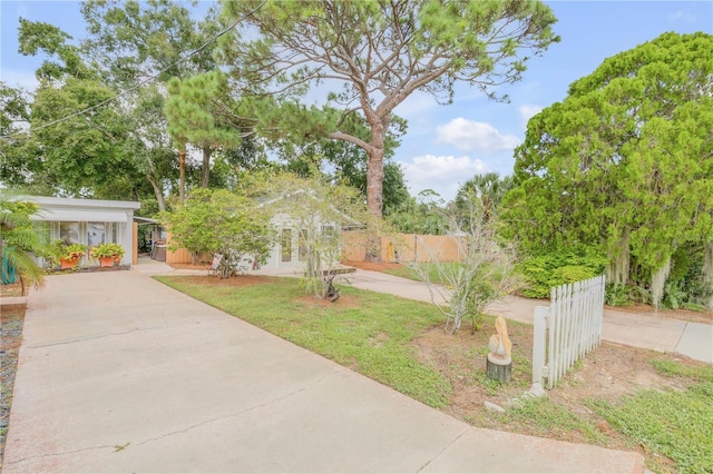 view of yard with concrete driveway and fence