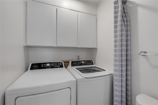 clothes washing area featuring cabinets and separate washer and dryer