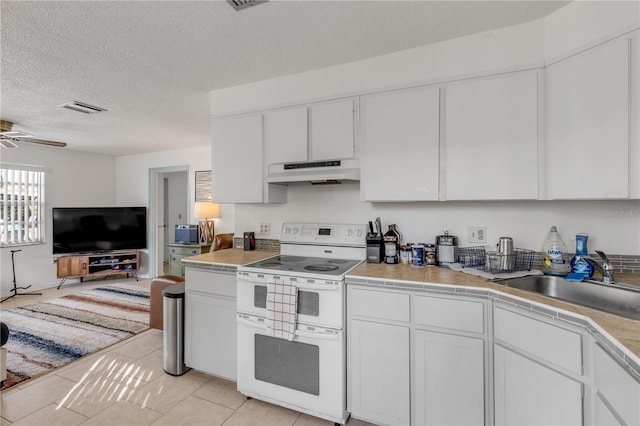 kitchen featuring light tile patterned flooring, sink, white cabinets, double oven range, and ceiling fan