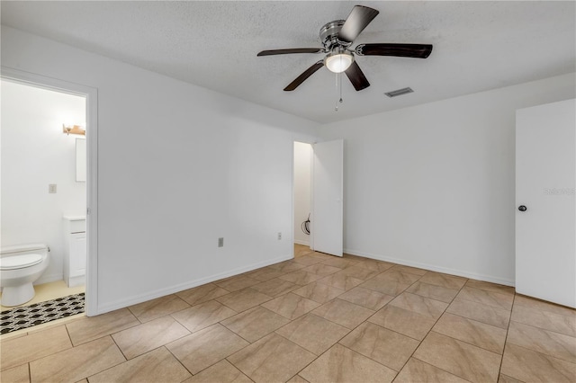 unfurnished bedroom featuring ceiling fan, ensuite bathroom, a textured ceiling, and light tile patterned flooring