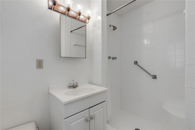 bathroom with vanity, toilet, and a tile shower