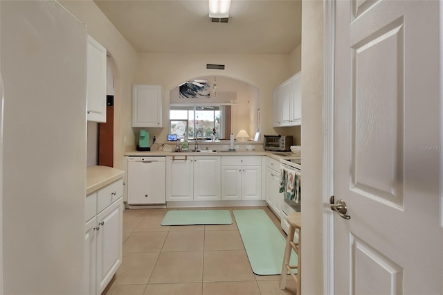 kitchen featuring light tile patterned floors, sink, dishwasher, range, and white cabinets