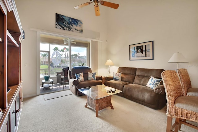 living room with ceiling fan, light carpet, and a high ceiling