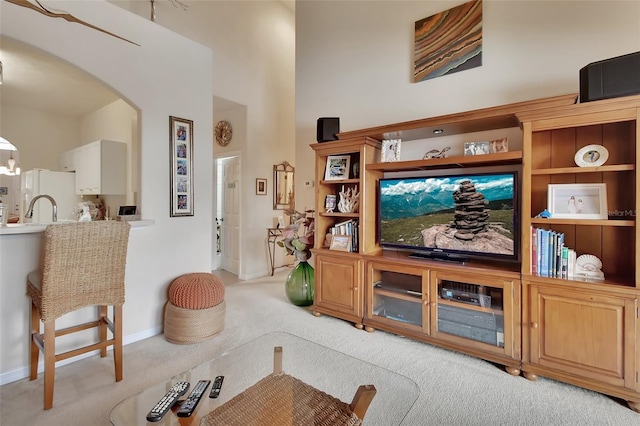 living room with sink, a towering ceiling, and light colored carpet