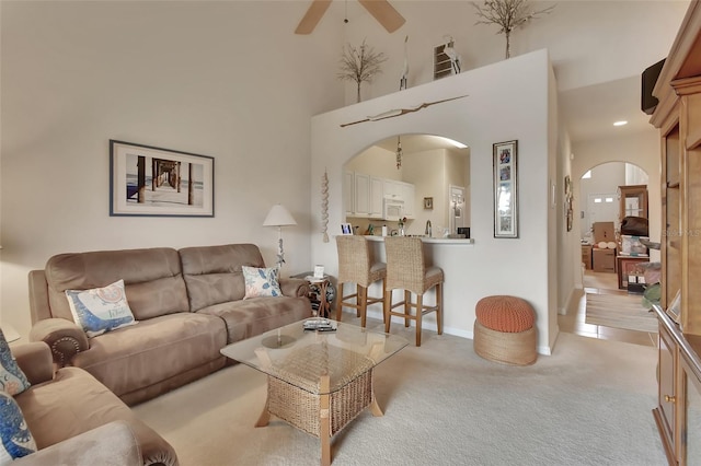 living room with light carpet, ceiling fan, and a high ceiling