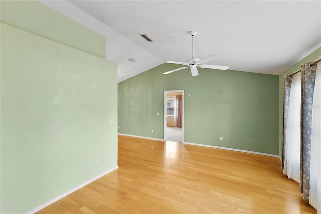 spare room featuring lofted ceiling, baseboards, visible vents, and wood finished floors