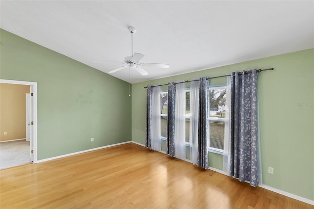 unfurnished room featuring a ceiling fan, vaulted ceiling, baseboards, and wood finished floors