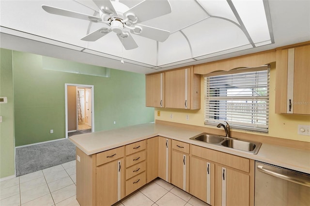 kitchen featuring dishwasher, a peninsula, a sink, and light brown cabinetry