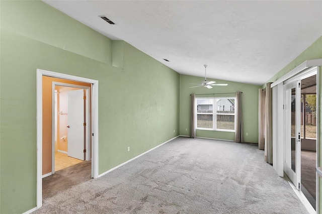 empty room with vaulted ceiling, carpet floors, visible vents, and baseboards