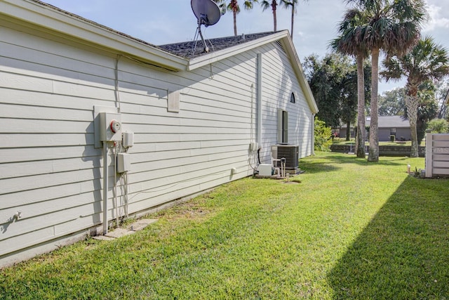 view of side of home with central AC unit and a lawn