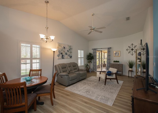 living room with hardwood / wood-style flooring, ceiling fan with notable chandelier, and high vaulted ceiling