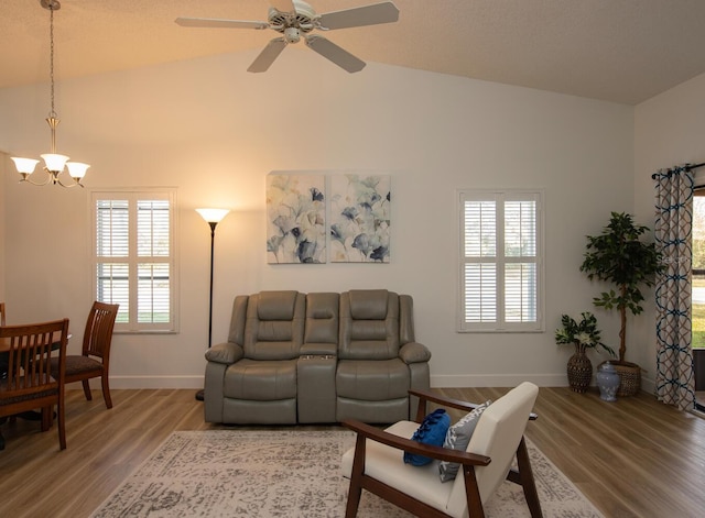 living room featuring ceiling fan with notable chandelier, wood-type flooring, and high vaulted ceiling