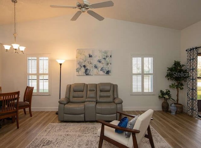 living room with hardwood / wood-style flooring, ceiling fan with notable chandelier, and high vaulted ceiling