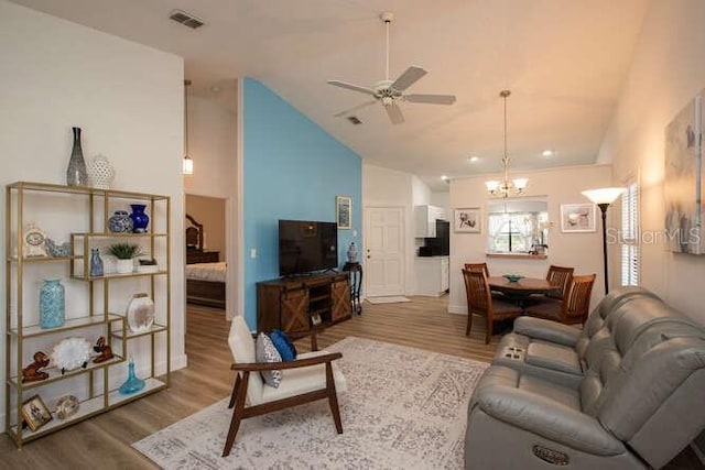 living room featuring high vaulted ceiling, wood-type flooring, and ceiling fan with notable chandelier