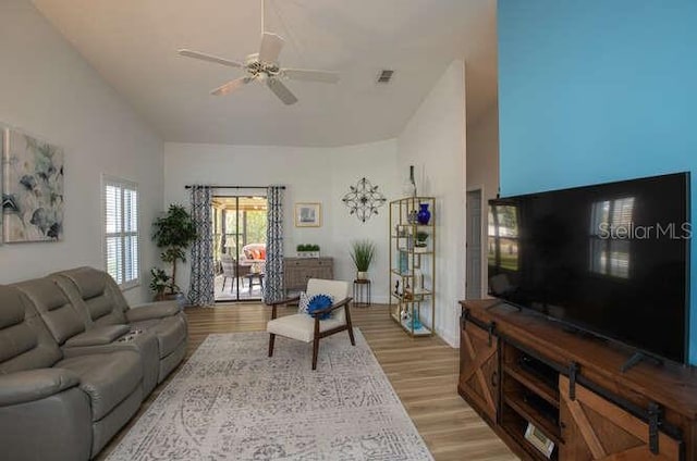 living room featuring light hardwood / wood-style flooring, high vaulted ceiling, and ceiling fan