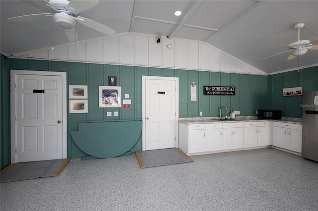 interior space featuring vaulted ceiling, stainless steel refrigerator, sink, white cabinets, and ceiling fan