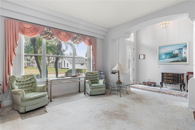 living area with carpet flooring, a chandelier, and ornate columns