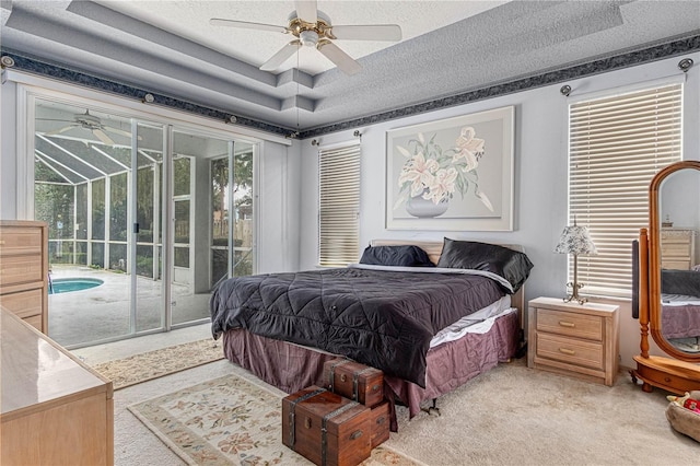 carpeted bedroom with ceiling fan, a raised ceiling, a textured ceiling, and access to outside