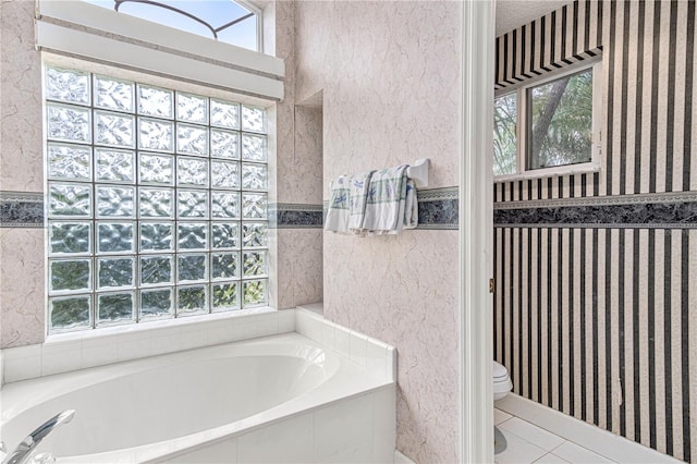 bathroom with a relaxing tiled tub, a textured ceiling, tile patterned floors, and toilet