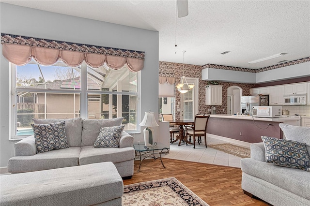 living room featuring ceiling fan, a textured ceiling, and light hardwood / wood-style flooring