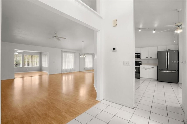 kitchen with stainless steel appliances, white cabinetry, a towering ceiling, and ceiling fan with notable chandelier