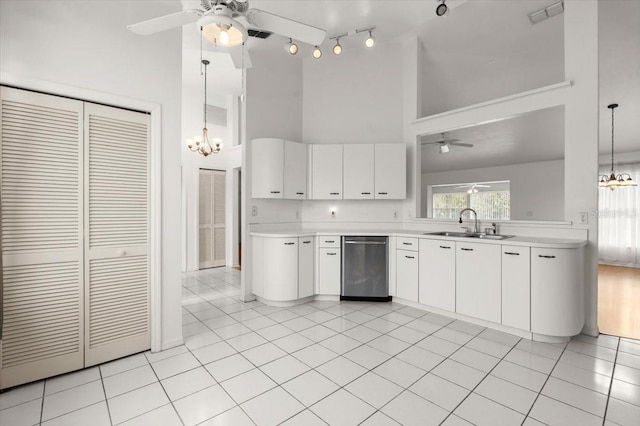 kitchen featuring sink, dishwasher, white cabinets, pendant lighting, and a high ceiling