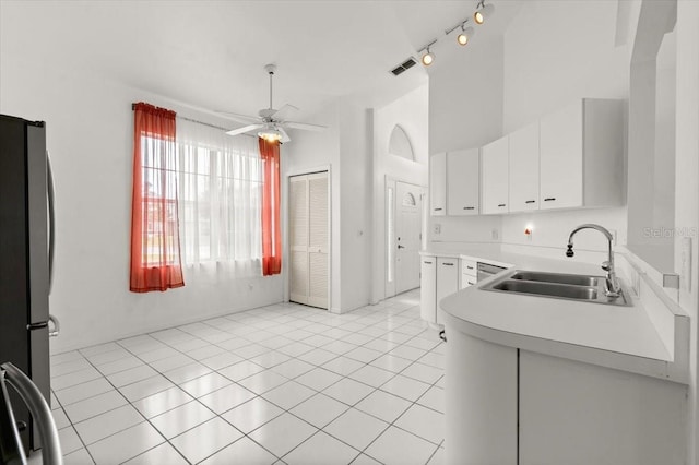 kitchen with sink, light tile patterned floors, stainless steel fridge, ceiling fan, and white cabinetry