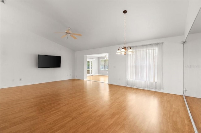 unfurnished living room with ceiling fan with notable chandelier, light hardwood / wood-style flooring, and vaulted ceiling