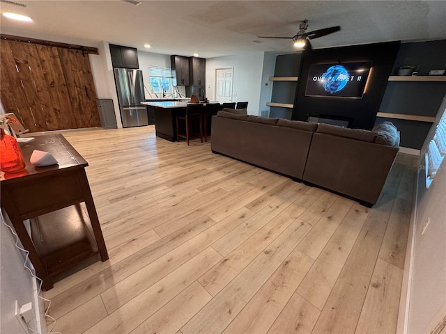 living room with ceiling fan and light wood-type flooring